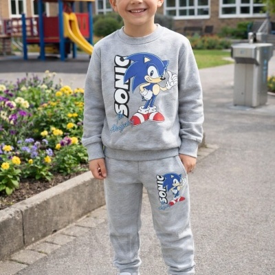 Menino a sorrir vestido com conjunto cinza claro com estampado Sonic the Hedgehog ao ar livre