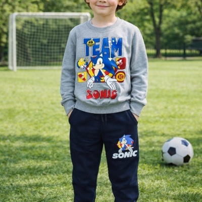 Menino com conjunto de treino cinza e azul com estampas de Sonic em campo de futebol