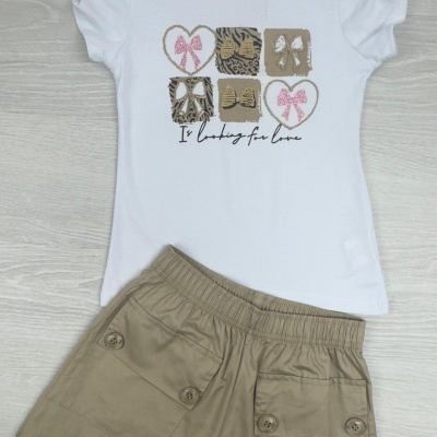 Conjunto infantil com t-shirt branca estampada e calções bege sobre chão claro