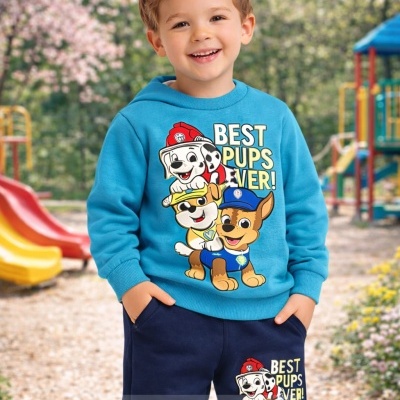 Criança com conjunto azul e estampado de cães animados em parque infantil.