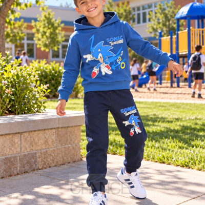 Menino a sorrir a usar conjunto azul com estampas de Sonic the Hedgehog em parque escolar.