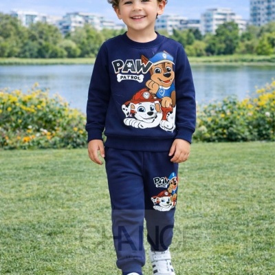 Menino com conjunto azul escuro com personagens PAW PATROL num parque