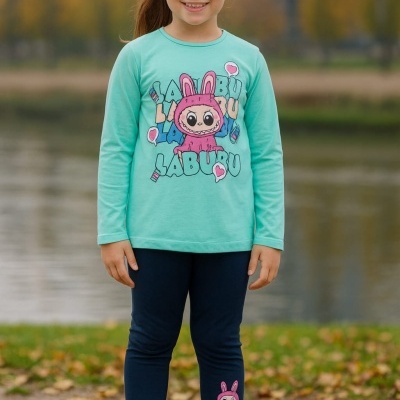 Menina com camisola verde água e leggings azuis com estampas coloridas, em parque.