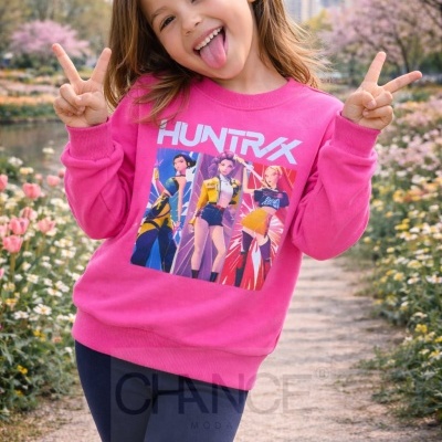 Camisola rosa com estampa colorida de personagens e texto HUNTRIX, usada por criança ao ar livre