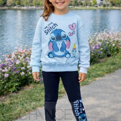 Menina com roupa azul clara e preta com estampa Stitch em ambiente exterior junto à água