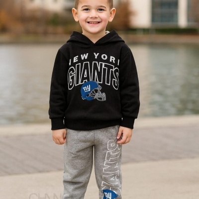 Criança com roupa desportiva New York Giants junto a corpo de água