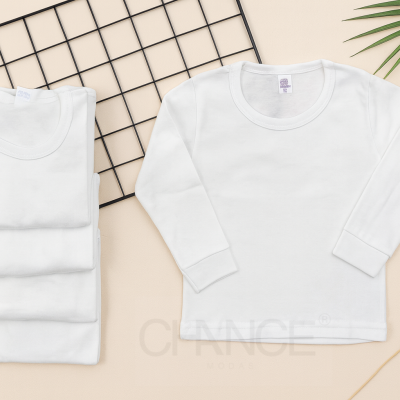 Camisolas brancas de manga comprida dobradas e estendidas sobre superfície bege com rede preta e folhas decorativas