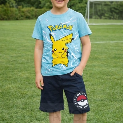 Menino de pé num campo de futebol a vestir camiseta azul com Pikachu e calções pretos com estampa de Pokébola.