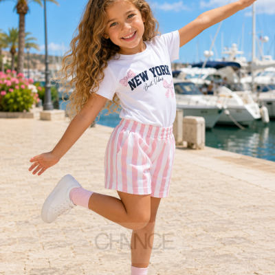 Menina com roupa casual sorridente junto a marina com barcos ao fundo.