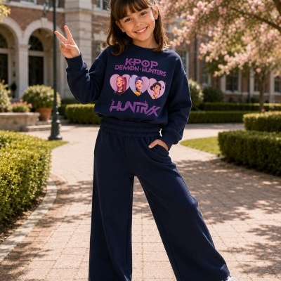 Menina com conjunto azul escuro com estampado K-POP em ambiente exterior com árvores e edifício