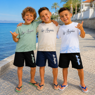 Três miúdos com camisolas e bermudas estampadas com Los Angeles STAY TRUE junto ao mar