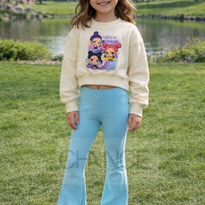 Menina com camisola bege desenhada, calças azuis e ténis brancos