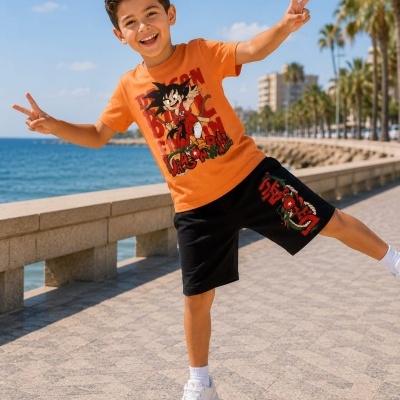 Criança com t-shirt laranja e calção preto com estampado Dragon Ball ao ar livre junto ao mar e palmeiras