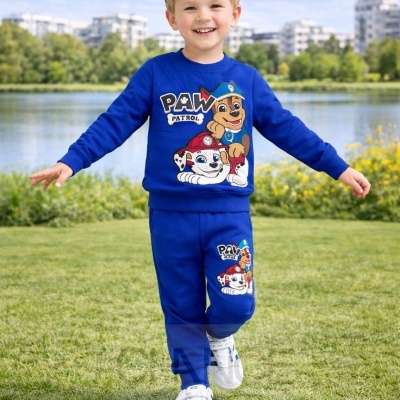 Menino loiro com conjunto azul PAW Patrol ao ar livre com relva e lago