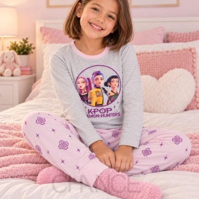 Menina sorridente sentada com pijama KPOP em quarto rosa acolhedor
