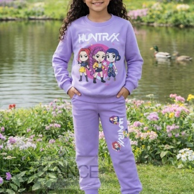 Menina com conjunto lilás ilustrado com personagens de desenho animado em parque junto a lago