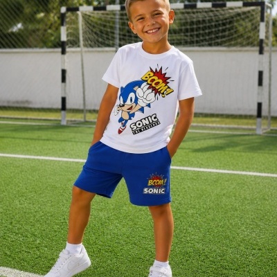 Menino com t-shirt branca e calção azul com estampa do Sonic em campo de futebol