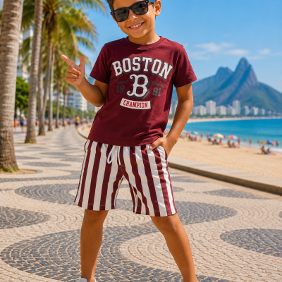 Menino com t-shirt BOSTON bordô e calções às riscas em calçada à beira-mar
