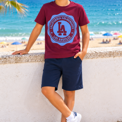 Criança com camisola castanha e calções azuis junto à praia