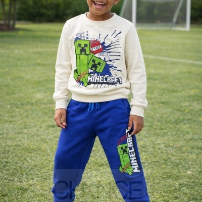 Menino a usar camisola bege e calças azuis com estampados Minecraft num campo de futebol