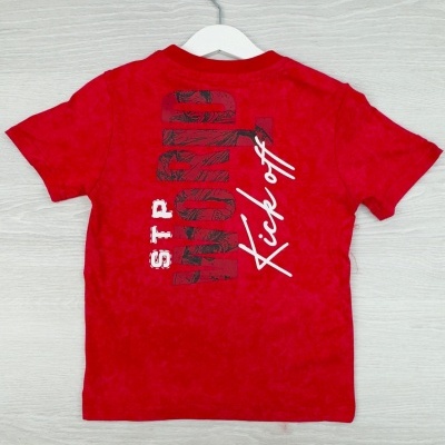 T-shirt vermelha de manga curta com estampa preta e branca nas costas pendurada num cabide branco