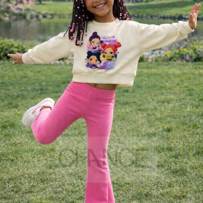 Menina com sweatshirt bege e calças rosa num parque verdoso perto de lago