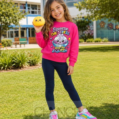 Menina com roupa colorida e ténis com luzes, segurando brinquedo amarelo feliz, em relvado junto a edifício escolar