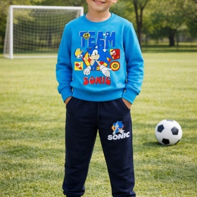 Menino com conjunto azul e preto do Sonic num campo de futebol