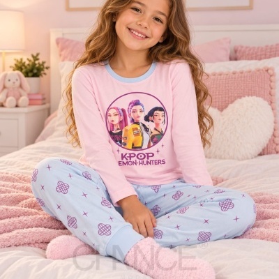 Criança sentada com pijama rosa e azul claro, estampado com personagens e texto KPOP EMON HUNTERS.