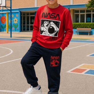 Rapaz com conjunto casual vermelho e azul com tema NASA em campo desportivo com bola de futebol