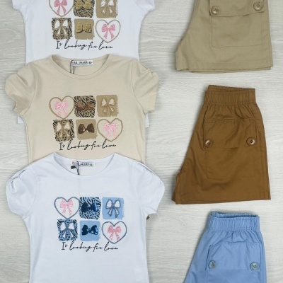 Três conjuntos de roupa para crianças com t-shirts e bermudas em cores bege, castanho, azul e branco.