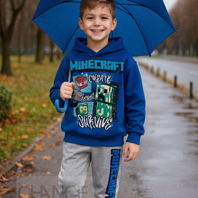 Criança com hoodie azul e calças cinza segurando sombrinha azul num parque molhado.
