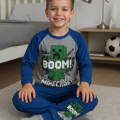 Menino sentado no chão com pijama azul e cinzento de Minecraft com estampado verde e texto BOOM! MINECRAFT.