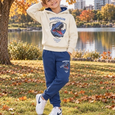 Menino vestido com conjunto bege e azul com estampa de dinossauro, em parque de outono