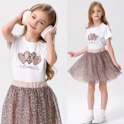 Menina com roupa branca e saia de tule com padrão de leopardo
