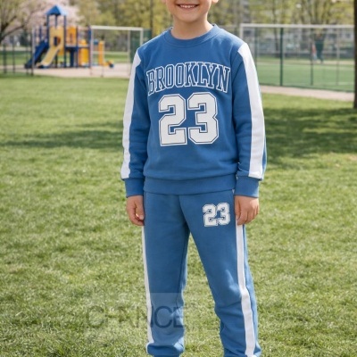 Rapaz com conjunto desportivo azul com texto BROOKLYN 23 em parque com relva verde