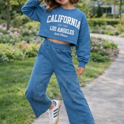 Menina vestindo conjunto desportivo azul com sweat cropped e calças largas e ténis brancos com riscas azuis