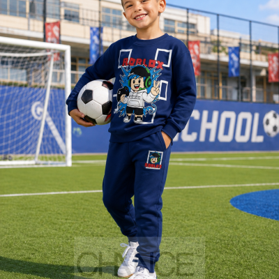 Menino com conjunto de fato de treino azul escuro Roblox segurando bola de futebol num campo de futebol