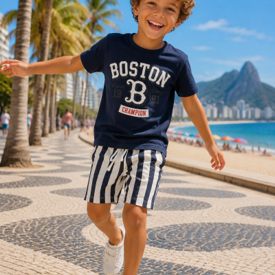 Menino vestido com camisola azul e calções de riscas na praia com palmeiras ao fundo