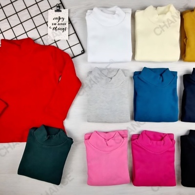 Onze camisolas de gola alta coloridas sobre superfície branca com cartão decorativo