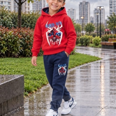 Menino com hoodie vermelho e calças de ganga azuis com desenhos do Homem-Aranha e ténis brancos ao ar livre num passeio molhado.