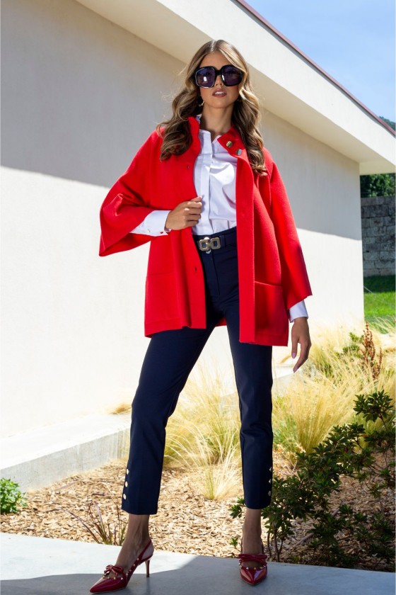 Mulher com casaco vermelho, camisa branca, calças azul-escuras e sapatos vermelhos ao ar livre