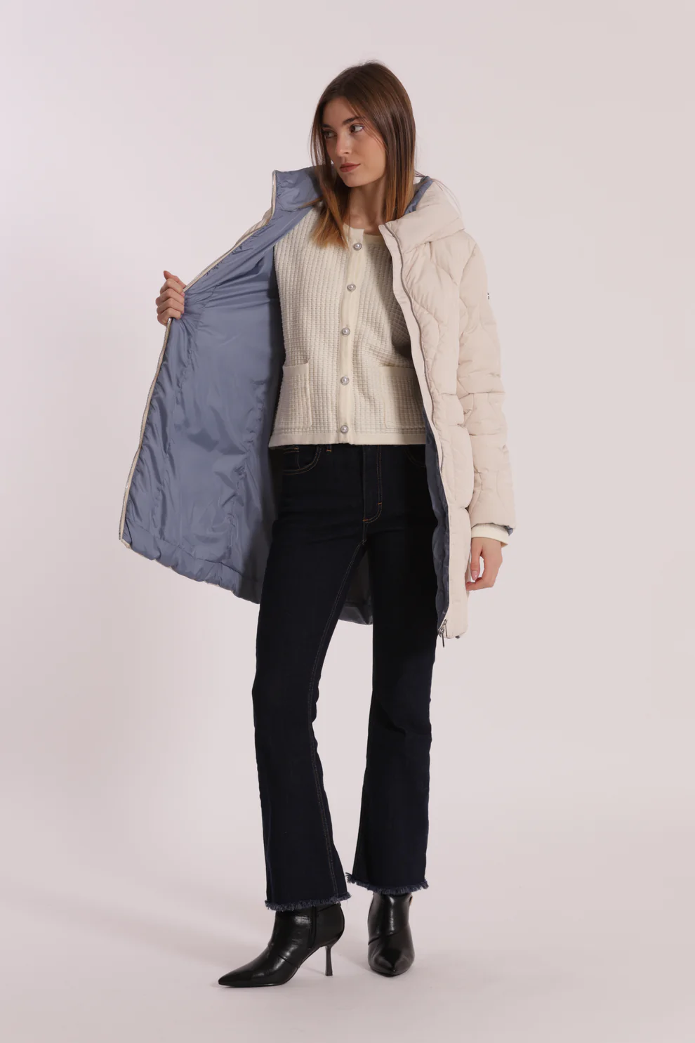 Mulher com casaco bege e roupa casual sobre fundo branco