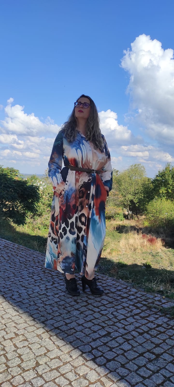 Vestido comprido com padrão colorido abstrato e calçado preto em ambiente exterior