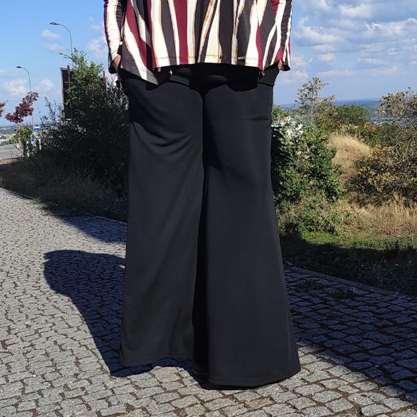 Calças pretas largas com blusa às riscas num passeio exterior