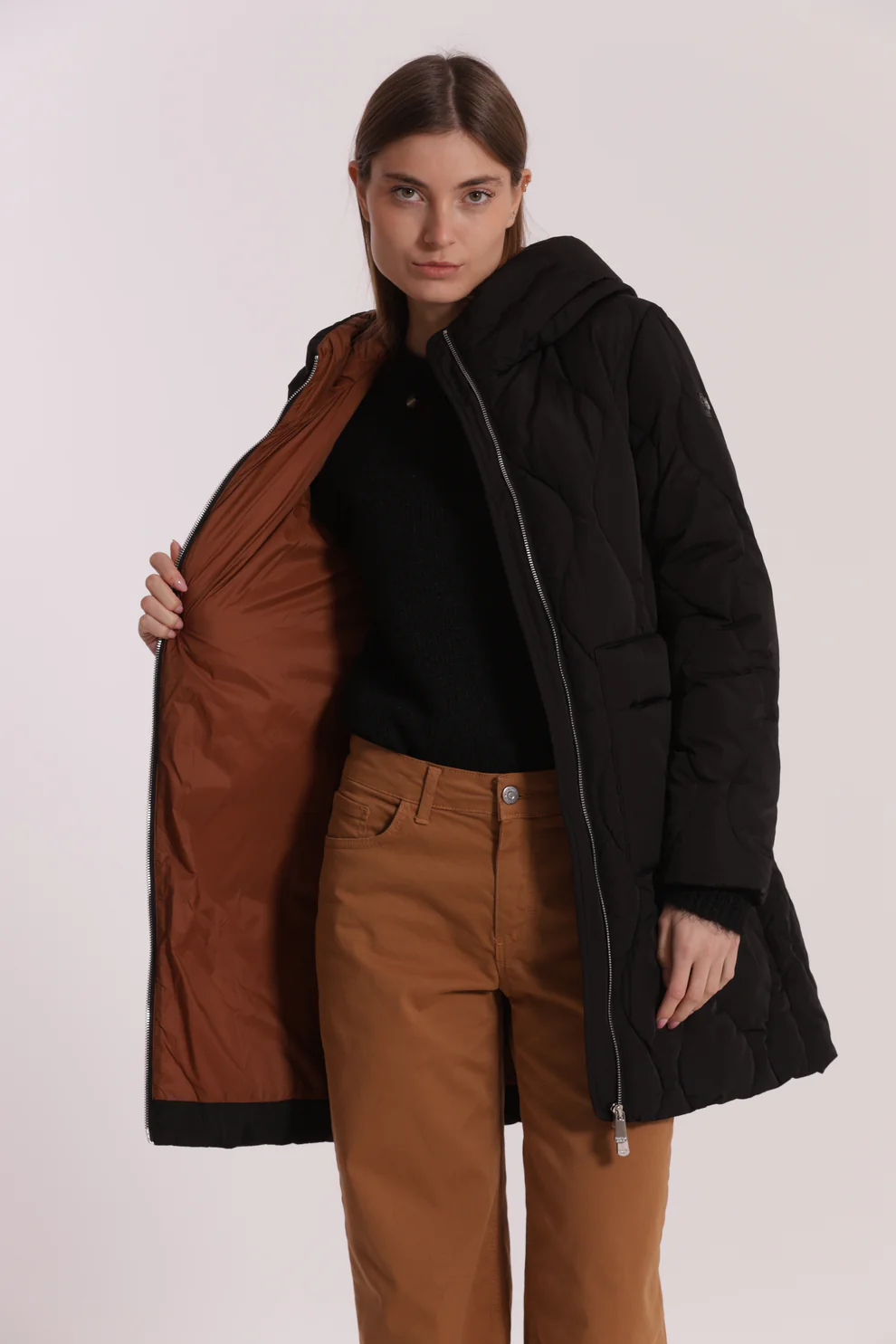 Casaco acolchoado preto comprido com interior castanho e mulher a mostrar o interior