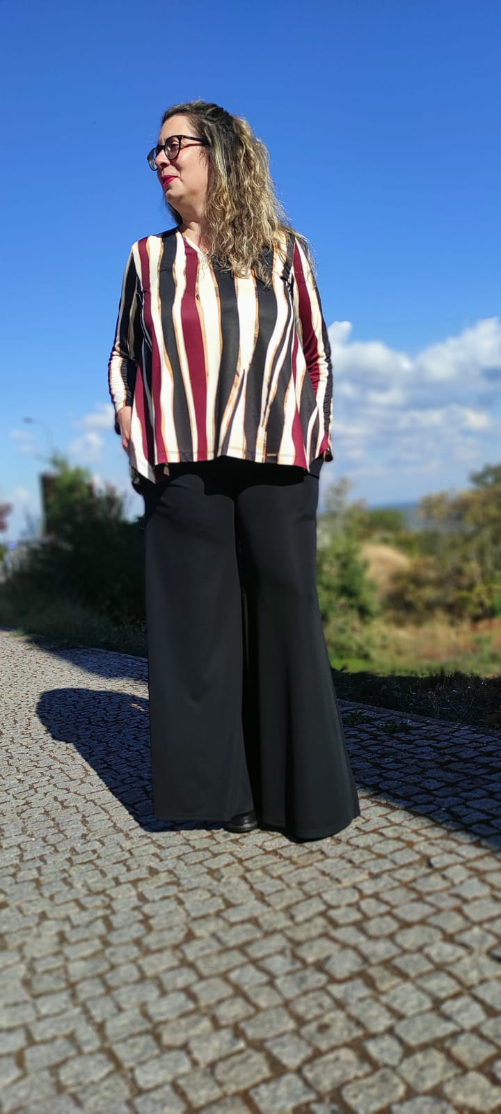 Mulher com blusa às riscas e calças largas pretas ao ar livre