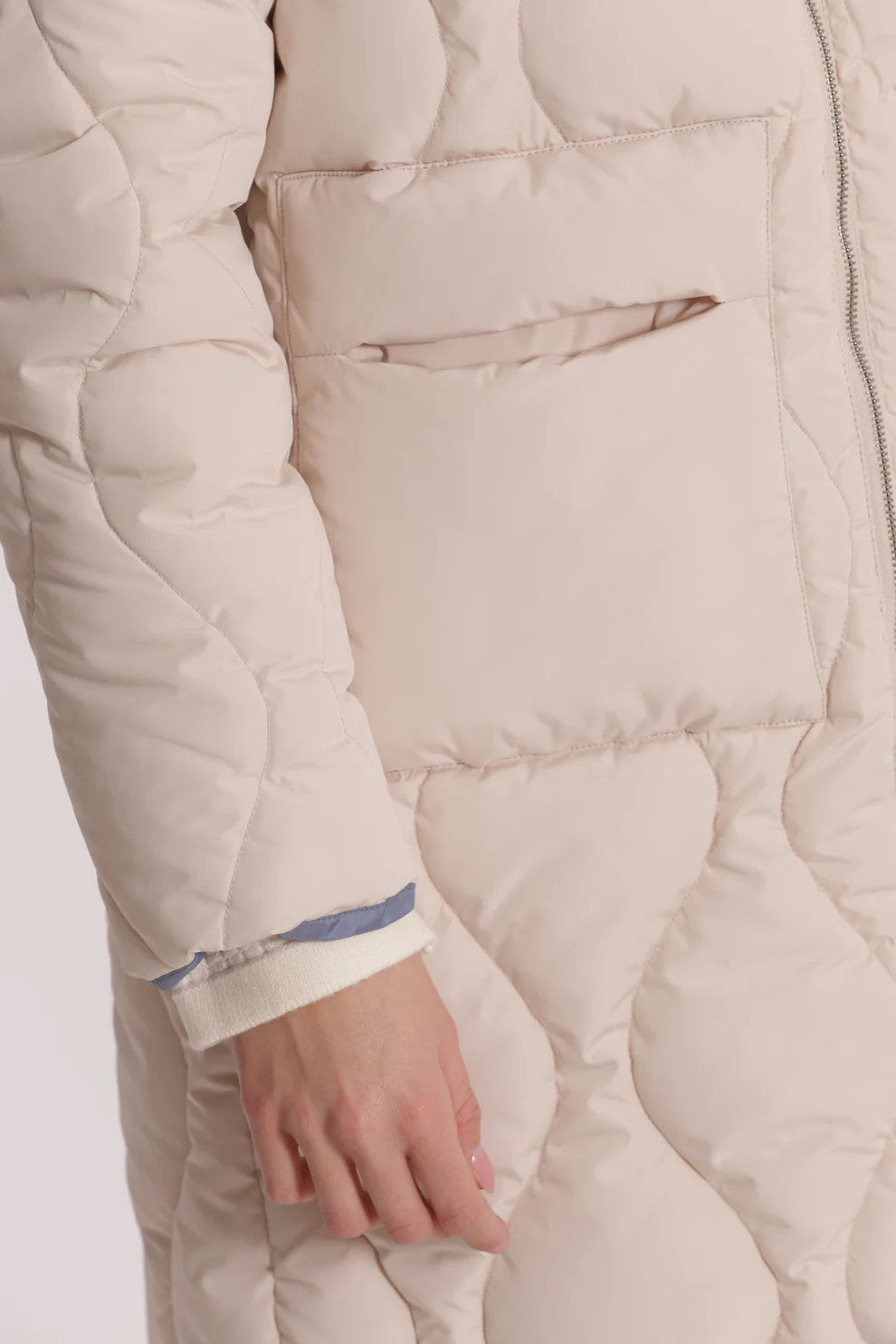 Casaco acolchoado bege claro com bolso frontal e padrão de costuras onduladas