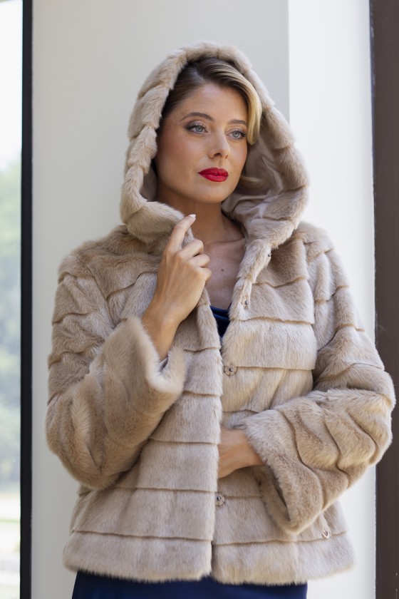 Casaco de pele bege com capuz e botões, usado por mulher.