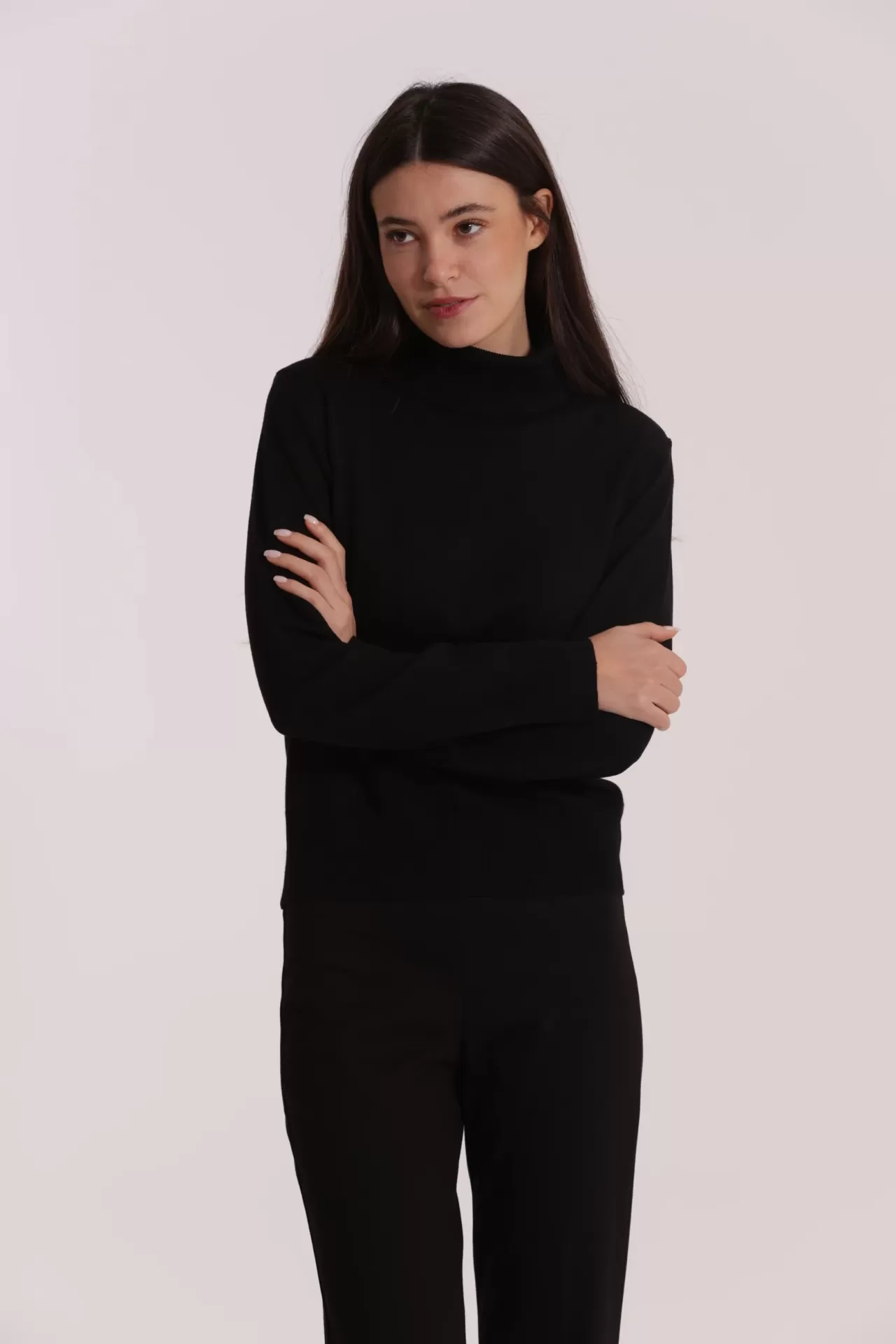 Mulher com camisola preta de gola alta e calças pretas